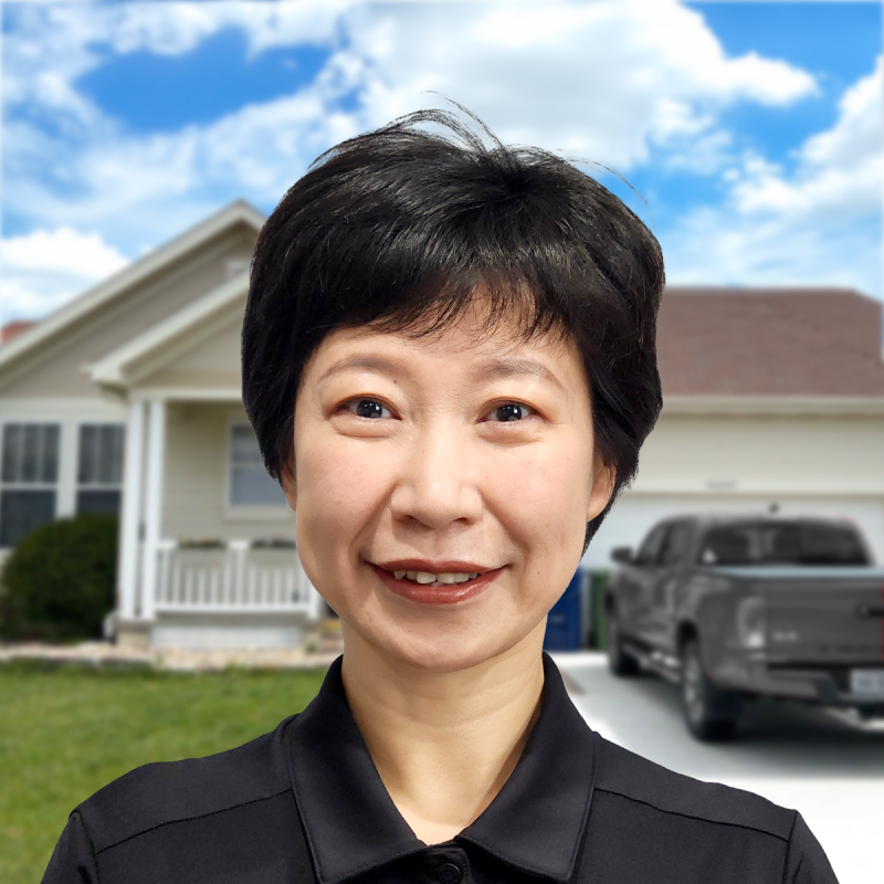 Smiling professional stands in front of a suburban home and a parked truck.