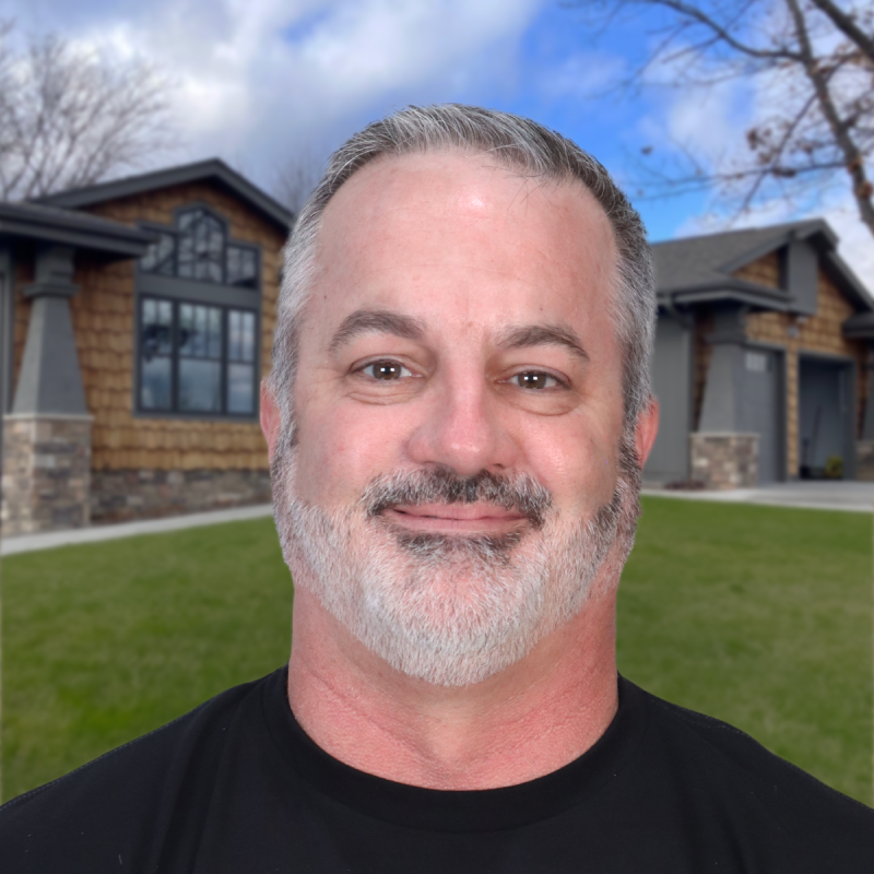 Man smiling in front of a modern house with a well-maintained roof.