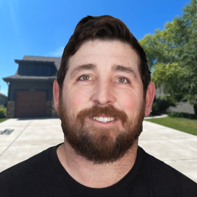Smiling man in front of a suburban house with clear blue skies.