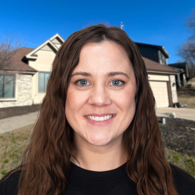 Smiling woman in front of a suburban home with a blue sky background.