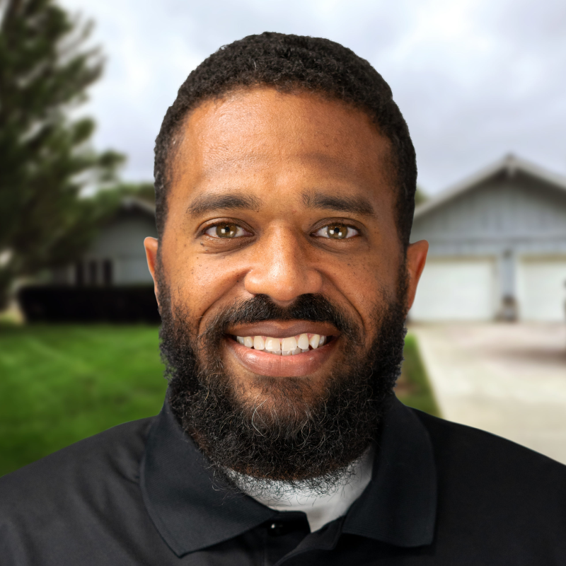 Smiling professional stands in front of a suburban house in Omaha.