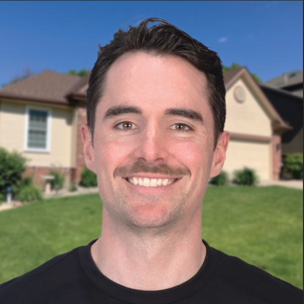 Smiling person standing in front of a suburban house with a manicured lawn.