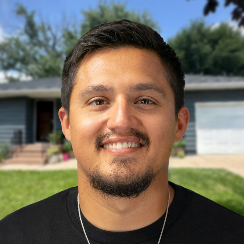 Smiling roofing expert in front of a house with a lush green yard.