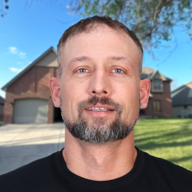 Man standing in front of a suburban home with a clear blue sky overhead.