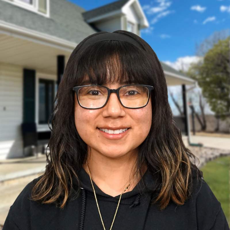 Smiling woman stands in front of a house with fresh roofing in Omaha.