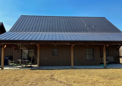 Metal roof on a wooden house showing landscaped backyard in clear daylight.